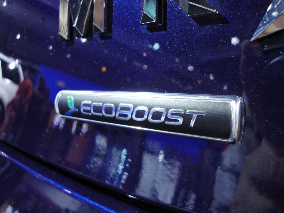 Close-up of an Ecoboost badge on a dark blue car. Some chrome lettering is visible above it