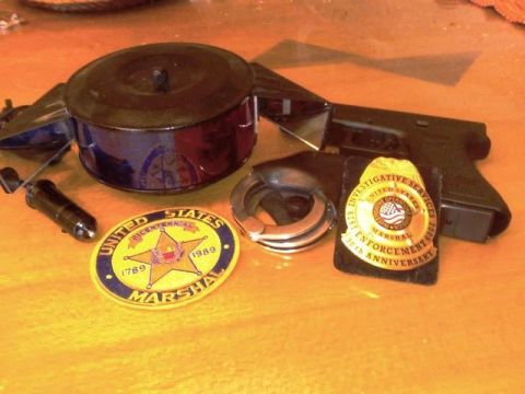 1991 Ford Crown Victoria - Collection of law enforcement items including a handgun, handcuffs, and patches.