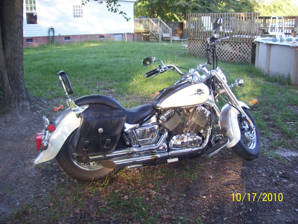White and black motorcycle with leather saddlebags parked on grass