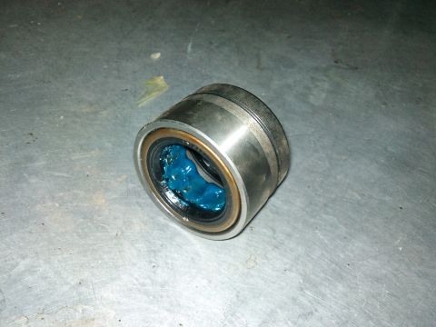 1998 Ford Crown Victoria - A wheel bearing filled with blue grease sits on a metallic surface, with a website address visible in the lower right corner.