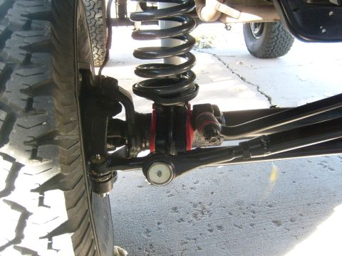 1986 Ford Bronco - A close-up view of the suspension system of a vehicle, showing the tire and coil spring.