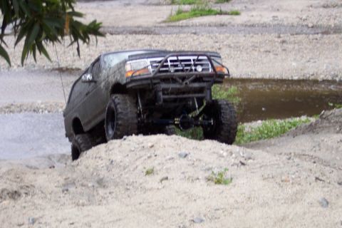 1995 Ford Bronco - This heavily modified SUV navigates a challenging off-road terrain with its large tires and lifted suspension.