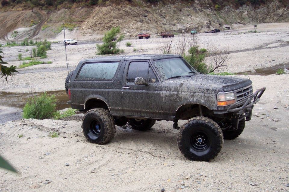 Mud-covered 1995 Ford Bronco with off-road tires and custom bumper