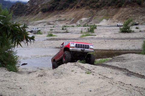 1995 Ford Bronco - Modified pickup truck navigates a challenging off-road terrain with multiple vehicles present.