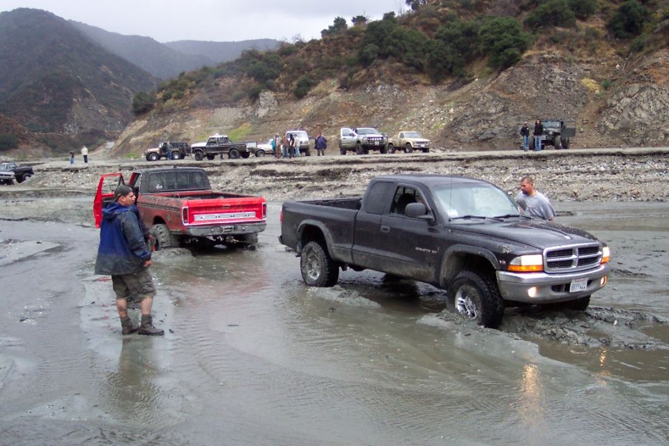 Black Dodge Dakota pickup truck in mud, front view. License plate visible