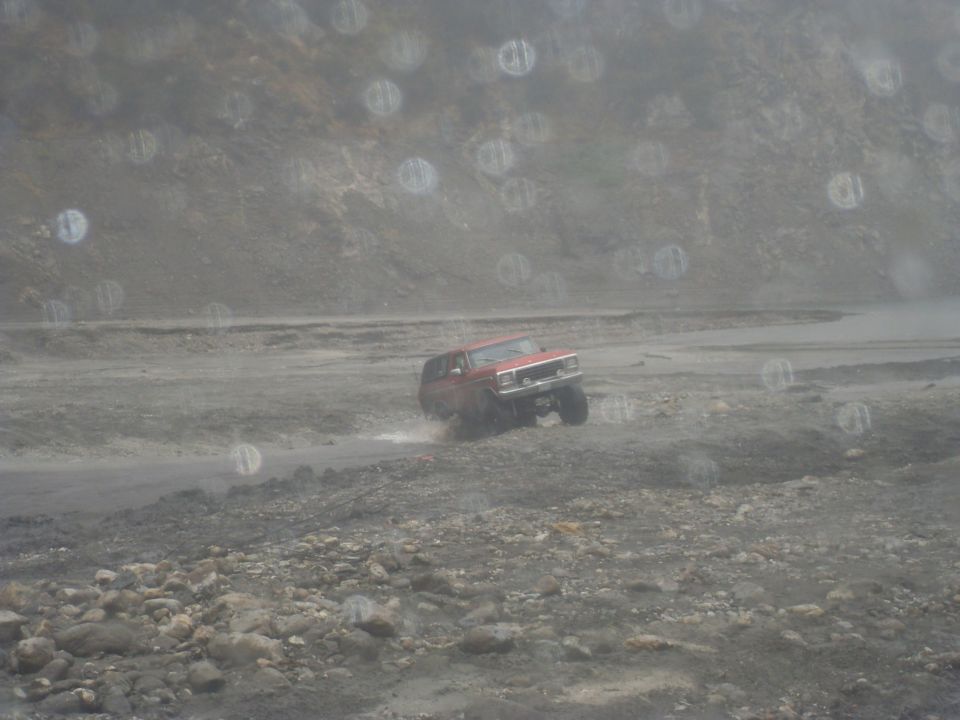 red SUV driving on a dirt road with mountains in the background