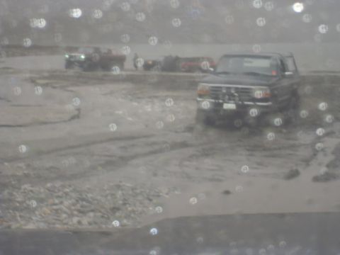 1979 Ford Bronco - Several vehicles are stuck in muddy terrain, including a dark SUV.