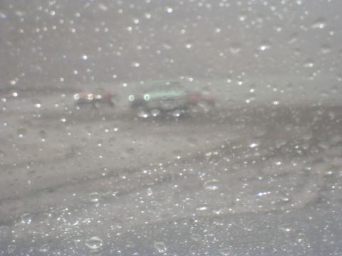 1979 Ford Bronco - Two vehicles are visible on the road, obscured by rain on the windshield.