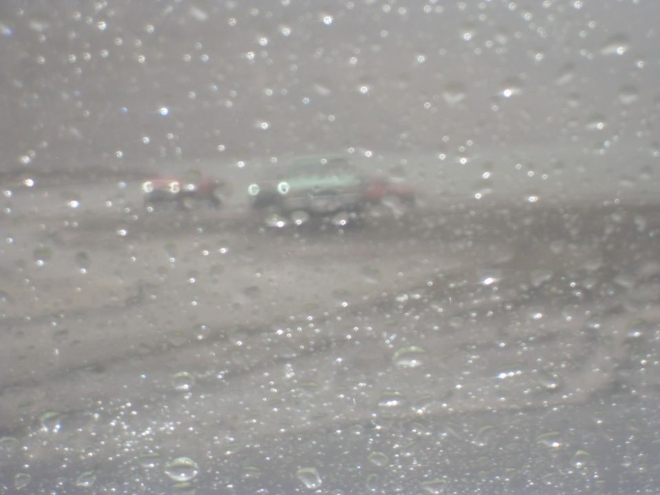 Two vehicles seen through a rain-streaked windshield