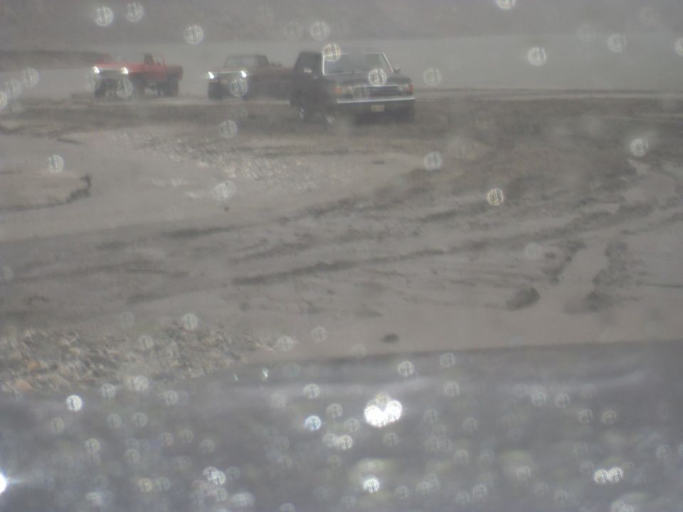Several pickup trucks are parked in a muddy, outdoor area. The image has many out-of-focus circles
