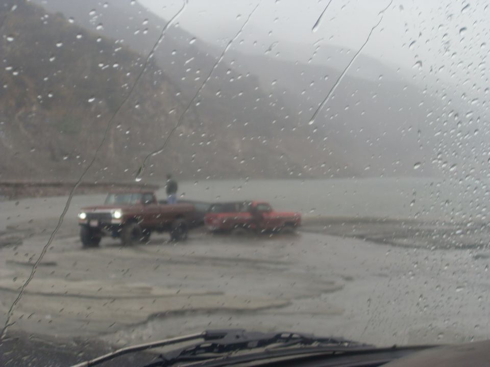 Two trucks in a muddy, rainy landscape
