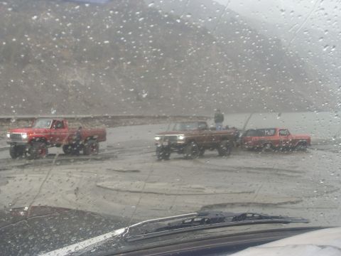 1979 Ford Bronco - Multiple trucks navigate a muddy, off-road course under overcast skies.