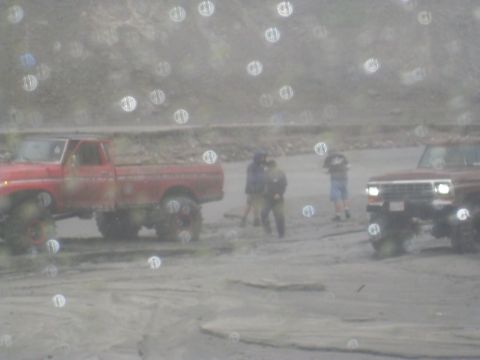 1979 Ford Bronco - Two off-road vehicles are parked in a dusty, outdoor location with several people standing around.