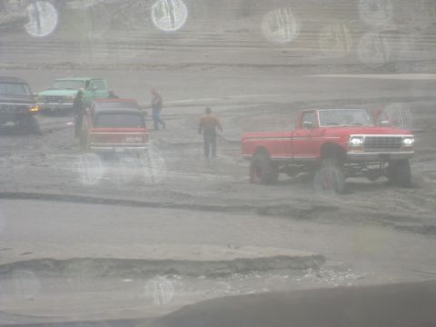 1979 Ford Bronco - Several vehicles, including a red pickup truck, navigate a muddy terrain.