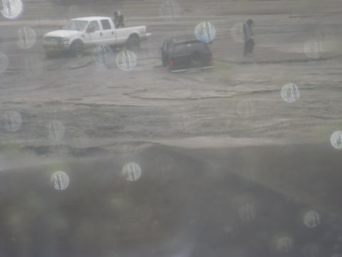 1979 Ford Bronco - Two vehicles are stuck in a muddy area, with people standing nearby.