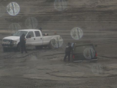 1979 Ford Bronco - Two vehicles are stopped in a muddy environment, with two individuals visible near them.