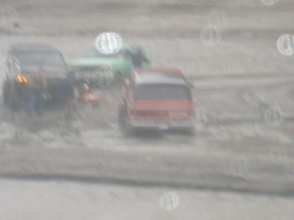 Red SUV from rear, with blue SUV and green truck behind in a blurry scene