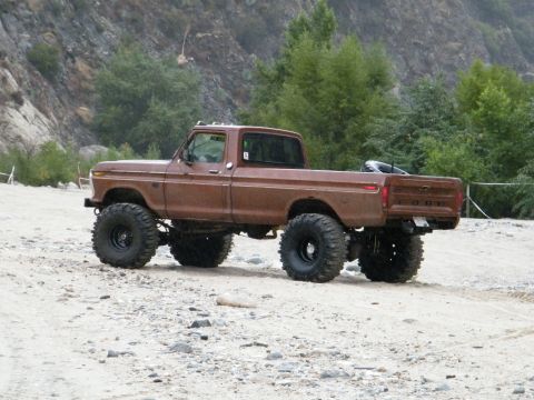 1982 Ford Bronco - This lifted Ford pickup truck is equipped with large off-road tires for terrain.