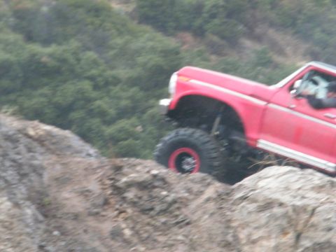 1982 Ford Bronco - This red SUV is navigating a challenging rocky terrain.