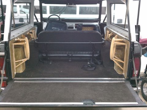 1975 Ford Bronco - The interior of a 1978 Ford Bronco is shown with its rear tailgate open, revealing folded jump seats.