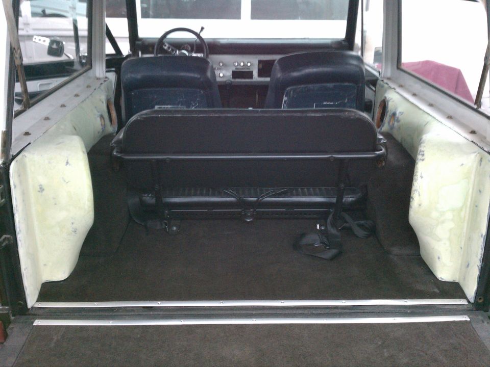 Interior of vintage SUV with black bench seat, front buckets and carpeted cargo floor