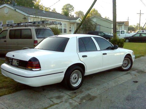 2005 Ford Crown Victoria - White 2005 Ford Crown Victoria sedan parked on a paved surface in front of houses.