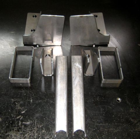 1996 Ford Bronco - Unassembled metal components for a vehicle part are laid out on a dark, textured surface.