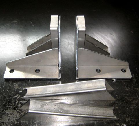 1996 Ford Bronco - Metal brackets and tubing are laid out on a dark, scratched surface.