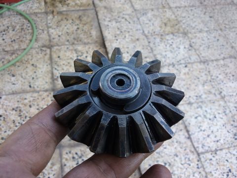 1998 Ford Crown Victoria - Close-up of a worn differential gear, held by a hand against a tiled background.