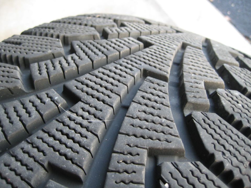 Close-up of a car tire tread with deep grooves and siping.