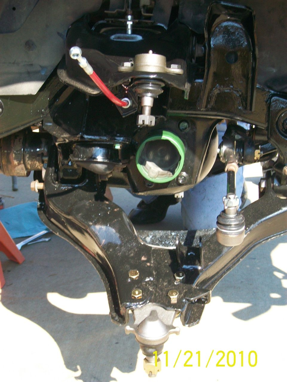 Black suspension parts with a red hose and green ring, viewed from below
