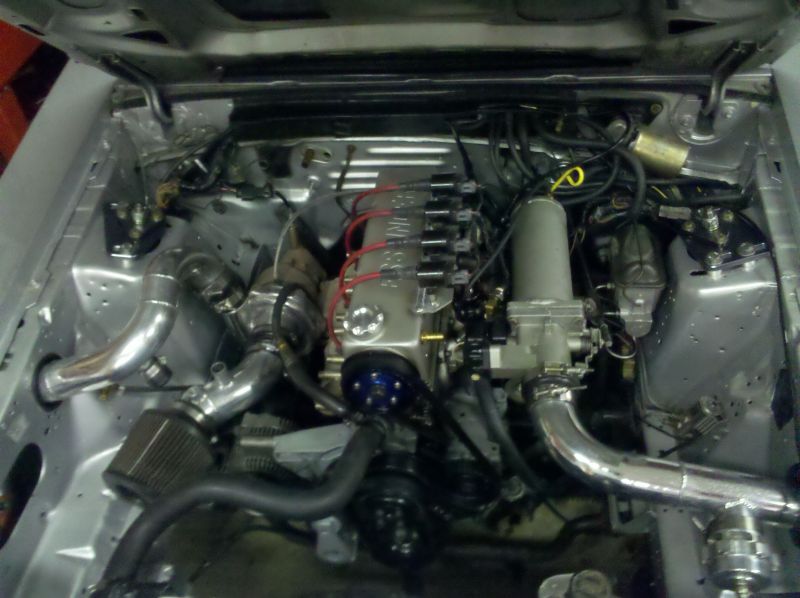 Modified engine bay with polished valve cover, red plug wires, and aluminum piping