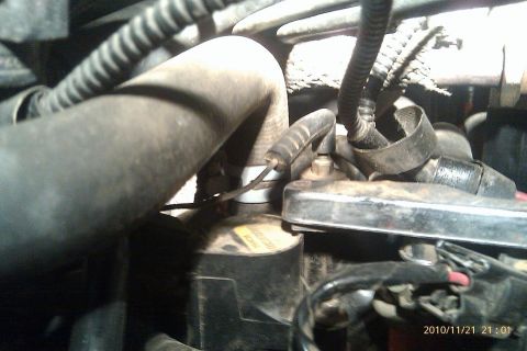 2000 Mercury Grand Marquis - Close-up view of an engine component with a yellow label and various hoses attached.
