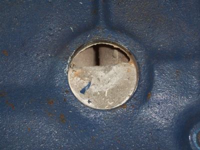 1969 Ford Torino - A hole is visible in a blue painted engine component, with some concrete-like material inside.