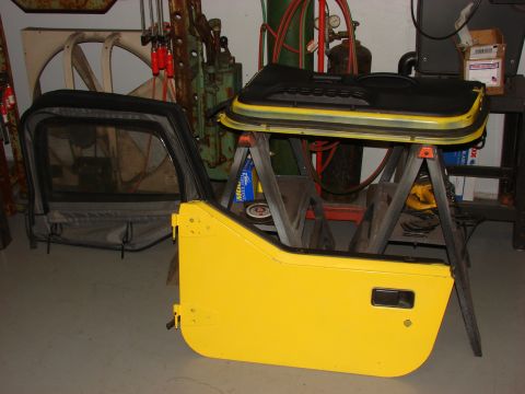 1993 Jeep YJ - Disassembled yellow Jeep doors and soft top are shown in a workshop setting.