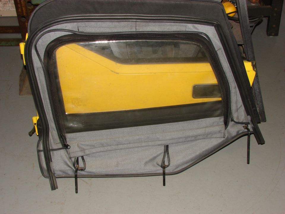 Yellow Jeep door with soft top window removed, showing grey fabric and black zippers