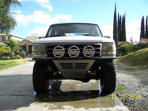 1995 Ford Bronco - A white Ford Bronco is shown from the front, modified with off-road accessories.