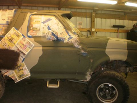 1995 Ford Bronco - A 1995 Ford Bronco is shown in profile, undergoing preparation for a camouflage paint job with its windows taped off.