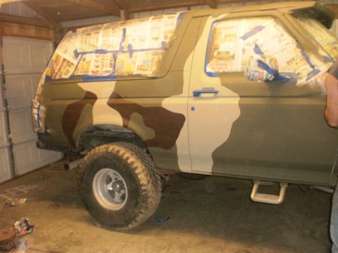 1995 Ford Bronco - A Ford Bronco is being painted with a camouflage pattern inside a garage.