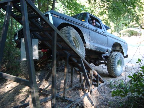1979 Ford Bronco - This lifted Ford Bronco is navigating a custom ramp in a forest setting.