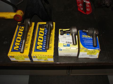 1993 Jeep Wrangler - Several Moog tie rod ends are laid out on a dark surface next to their packaging.