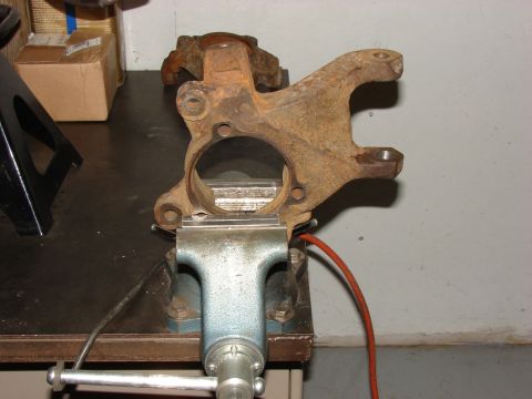 1993 Jeep Wrangler - A rusty steering knuckle is clamped in a vise, likely for repair or replacement.