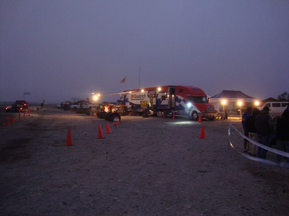 BFGoodrich semi-truck support rig at a dusty desert race pit at dusk with traffic cones