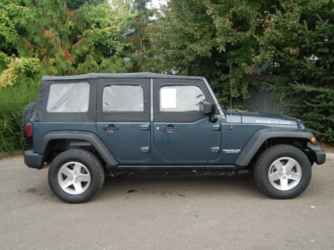 2005 Jeep Wrangler - Dark teal Jeep Wrangler Unlimited Rubicon shown from the side with a soft top and spare tire on the back.