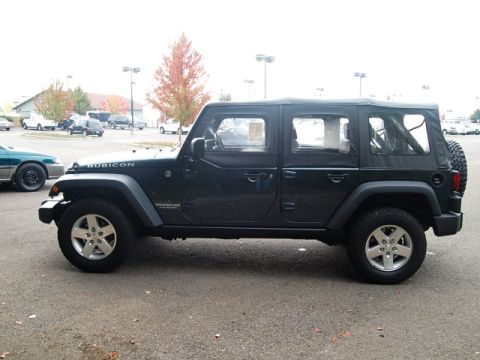 2005 Jeep Wrangler - A dark green Jeep Wrangler is parked in a lot, with other vehicles and trees in the background.