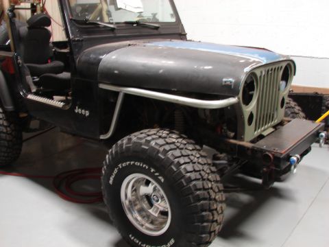 1993 Jeep Wrangler - This Jeep CJ-series features a green grille and an aftermarket bumper, with a partial blue stripe on the hood.