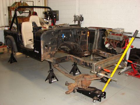 1993 Jeep Wrangler - The 1993 Jeep YJ is disassembled and supported by jack stands, revealing its chassis and engine bay.