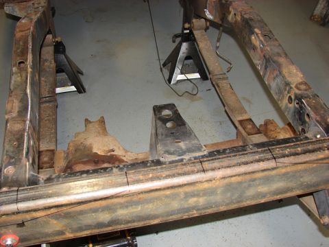 1993 Jeep Wrangler - The frame of a vehicle is elevated on jack stands, revealing its rusty undercarriage and suspension parts.
