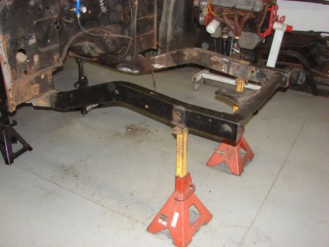 1993 Jeep Wrangler - The frame of a vehicle is supported by jack stands, with the engine partially visible.