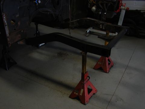 1993 Jeep Wrangler - The frame of a vehicle is elevated on red jack stands, suggesting it is undergoing maintenance or restoration.